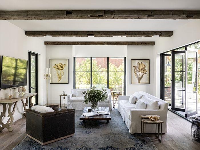 Clean residential living room with exposed beams and white sofas