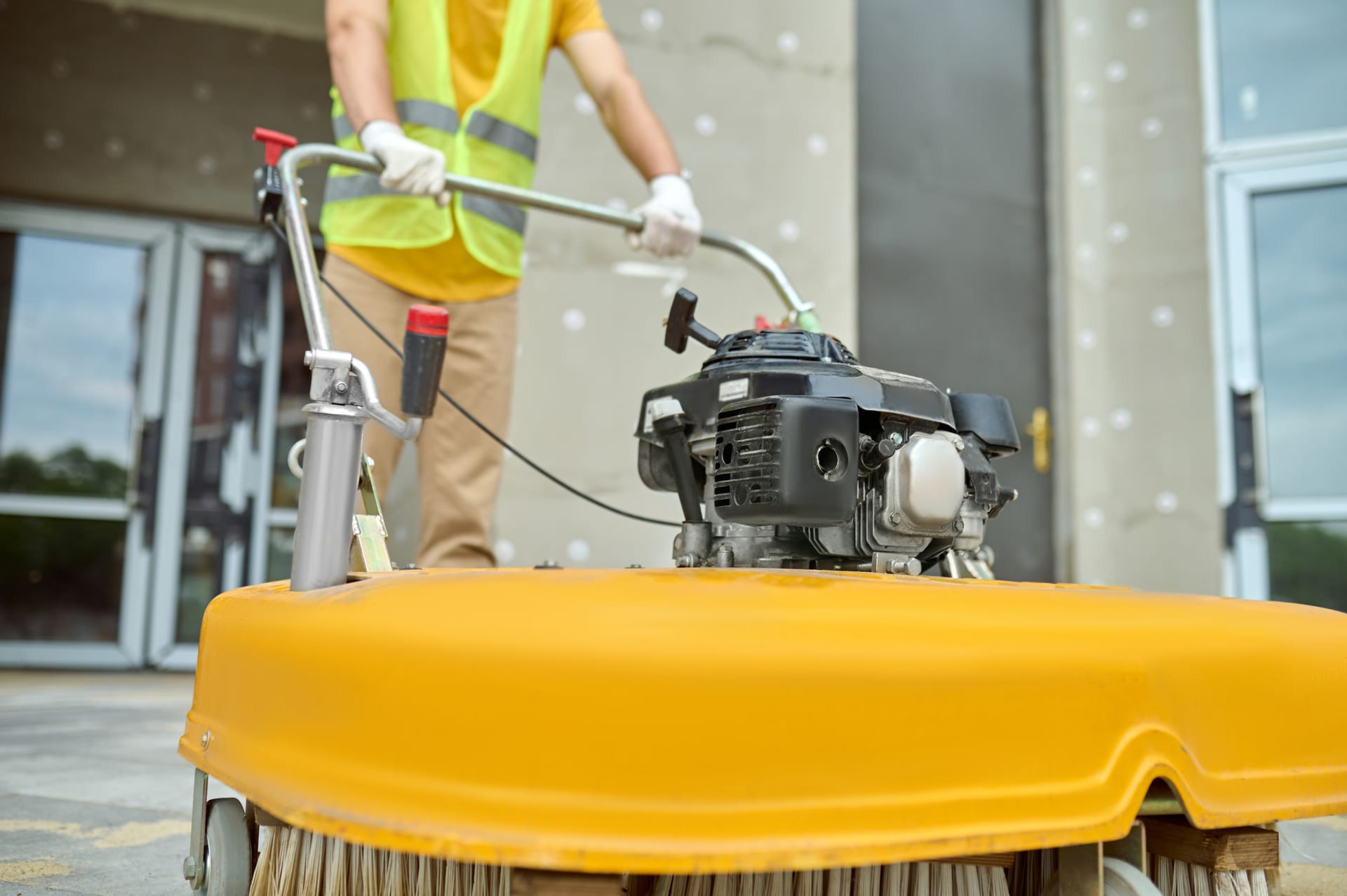 Worker operating an industrial sweeper at a construction site